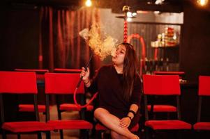 garota asiática fuma cachimbo de água no lounge bar. foto
