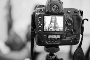 linda mulher afro-americana fazendo um vídeo para seu blog usando uma câmera digital montada em tripé. jovem blogueira ou vlogger na câmera. foto