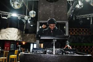 DJ afro-americano toca música em decks na boate. foto