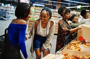 grupo de mulheres africanas com carrinhos de compras perto de produtos assados em um supermercado. foto