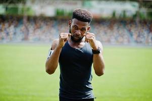 homem boxer atleta masculino americano africano em roupas esportivas fazendo alongamento no estádio. foto