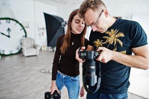 a equipe de dois fotógrafos olhando para o material de trabalho final da câmera no estúdio. foto