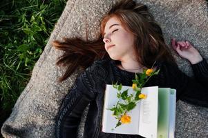 jovem morena deitada na manta com o livro. foto