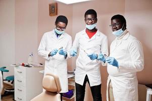 três colegas de médicos do sexo masculino afro-americanos com ferramentas em mãos na clínica. foto