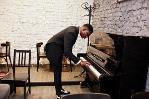 forte e poderoso homem afro-americano de terno preto tocar piano. foto