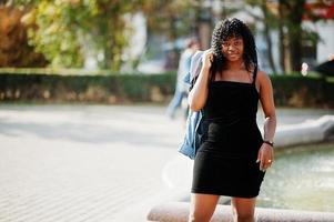 elegante na moda afro frança encaracolada posou no dia de outono em jaqueta jeans. modelo feminino africano negro contra fonte. foto