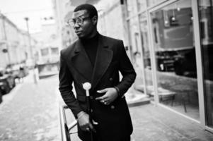 elegante cavalheiro afro-americano na elegante jaqueta preta, segurando a bengala retrô como balão de cana ou bengala com alça de bola de diamante dourado. homem afro elegante rico. foto