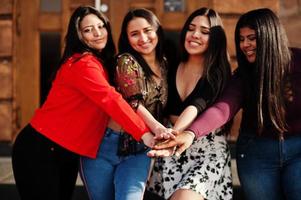 grupo de quatro meninas latinas felizes e bonitas do Equador posou na rua e de mãos dadas juntos. foto