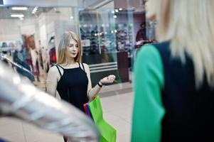 menina com sacolas de compras no shopping olhando manequins na vitrine. foto