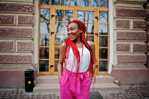 garota afro-americana na moda em calças cor de rosa e dreads vermelhos posou ao ar livre. foto