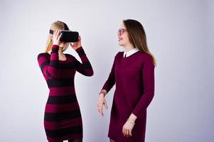 duas garotas de vestidos roxos experimentando óculos de realidade virtual no estúdio. foto