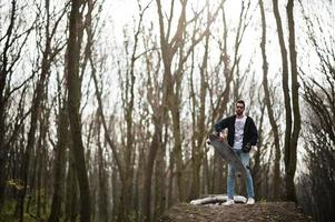 homem árabe de estilo de rua em óculos com longboard em madeira. foto