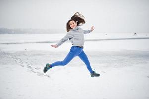 garota pulando engraçada no lago congelado em dia de inverno. foto