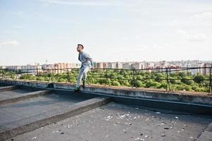 homem macho elegante sonhador de terno cinza e óculos posou no telhado. foto