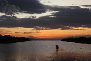 pescador em seu barco ao pôr do sol. barco de pescadores ao pôr do sol