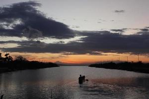 pescador em seu barco ao pôr do sol. barco de pescadores ao pôr do sol foto