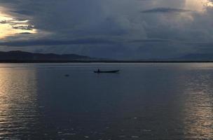 pescador em seu barco ao pôr do sol. barco de pescadores ao pôr do sol foto