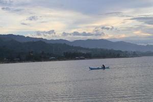 silhueta de pescador em seu barco foto