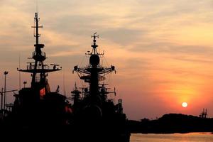 navio de guerra com pôr do sol atrás foto