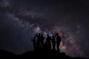 paisagem com via láctea, céu noturno com estrelas e silhueta de pessoas felizes em pé na montanha, fotografia de longa exposição, com grãos foto