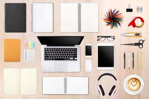 mesa do empresário com laptop, tablet smartphone e material de escritório em fundo de madeira foto