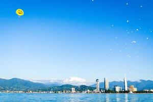 panorama batumi com parasailers no ar em pára-quedas amarelo em dia de céu azul claro. casal faz para-vela tocar na água. para-vela e segurança em esportes aquáticos foto