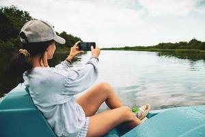 jovem turista caucasiana sente-se no pedalinho e tire fotos do lago e da natureza verde em kolkheti, geórgia