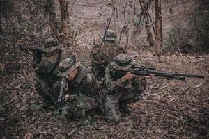 equipe de soldado do exército com metralhadora se movendo na floresta, soldado da milícia tailandesa em uniformes de combate na floresta, passeia pela patrulha inclinada na floresta tropical. foto