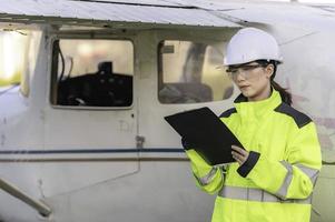 técnico consertando o motor do avião, engenharia aeroespacial feminina verificando motores de aeronaves, manutenção mecânica asiática inspeciona motor de avião foto