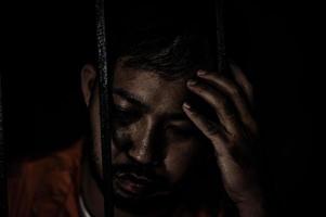 homem asiático desesperado na prisão de ferro, conceito de prisioneiro, povo da tailândia, espero ser livre, prisioneiros sérios presos na prisão foto