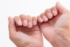 mãos de mulher mostrando unhas sem esmalte no fundo branco foto