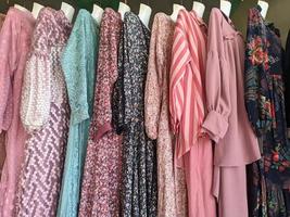 uma coleção de roupas femininas locais penduradas e vendidas em mercados tradicionais com várias cores e motivos foto