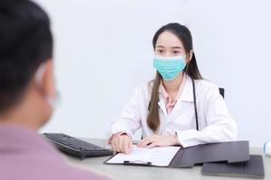 médica asiática está falando com um paciente homem no hospital. foto