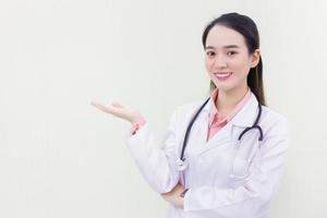 médica profissional asiática mostra a mão para apresentar algo enquanto olha para a câmera no fundo branco. foto
