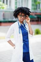 retrato de médica afro-americana com estetoscópio vestindo jaleco. foto