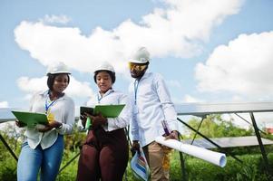 técnico americano africano verifica a manutenção dos painéis solares. grupo de três engenheiros negros reunidos na estação solar. foto