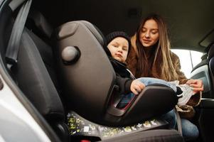 jovem mãe e filho no carro. assento de bebê na cadeira. conceito de condução de segurança. foto