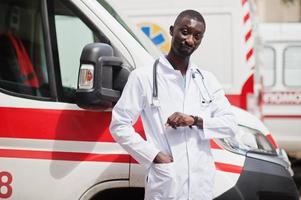 paramédico masculino africano em frente ao carro da ambulância. foto