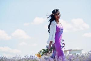 linda garota indiana usar vestido tradicional saree índia no campo de lavanda roxo. foto