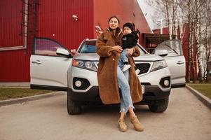 jovem mãe e filho ficam perto do carro suv. conceito de condução de segurança. foto