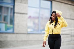 garota afro-americana hipster vestindo capuz amarelo posando na rua. foto