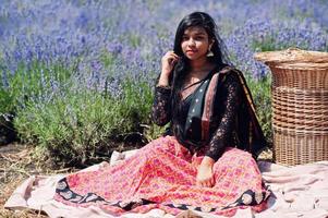 linda garota indiana usar vestido tradicional saree índia no campo de lavanda roxo. foto