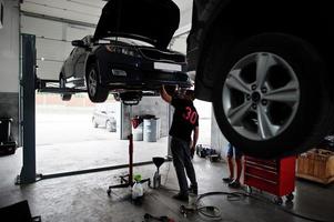 tema de reparação e manutenção de automóveis. mecânico de uniforme trabalhando em auto serviço. foto