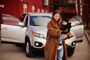 jovem mãe e filho ficam perto do carro suv. conceito de condução de segurança. foto