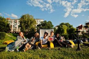 jovem grupo multiétnico de pessoas assistindo filme no poof no cinema ao ar livre. foto