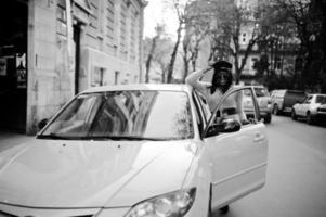 mulher afro-americana no vestido violeta e boné posou no carro amarelo. foto