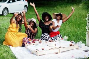 grupo de garotas afro-americanas comemorando a festa de aniversário e tilintando copos ao ar livre com decoração. foto