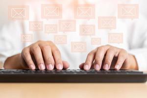 mão de mulher digitando no conceito de teclado de receber ou enviar ícone de e-mail na mesa de trabalho com laptop foto