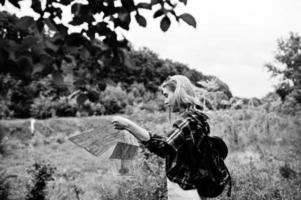 retrato de uma linda loira na camisa tartan andando com um mapa na zona rural. foto