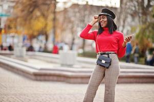 garota de moda afro-americana no boné de jornaleiro e bolsa posou na rua. foto